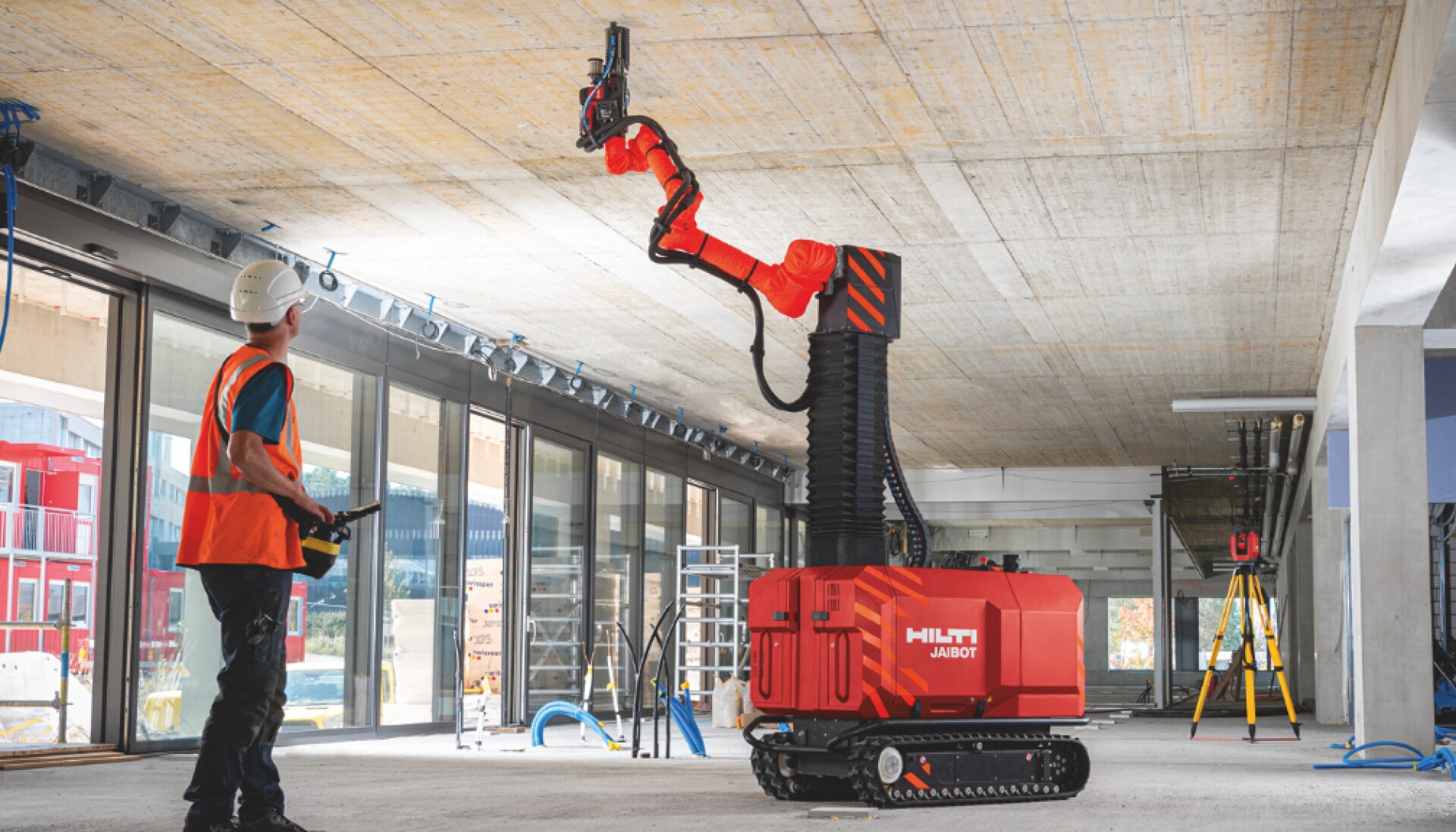 Construction worker safely operating ceiling drilling robot Jaibot on a jobsite