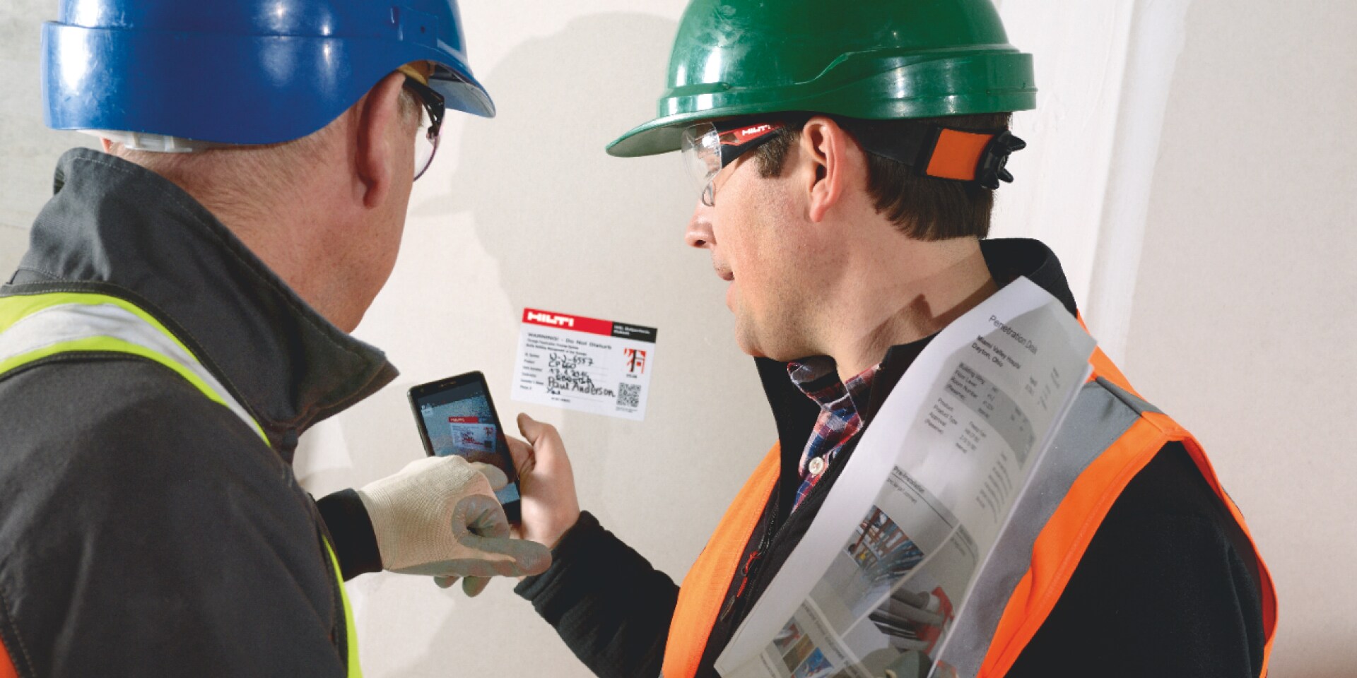 Photo of a maintenance and inspection team scanning a QR code using a mobile phone to access data on a firestop system.